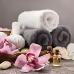 Phot of rolled towels, essential oils, and flowers