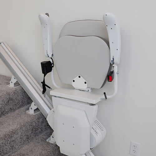 stair lift installed along carpeted stairs folded up in a stored position